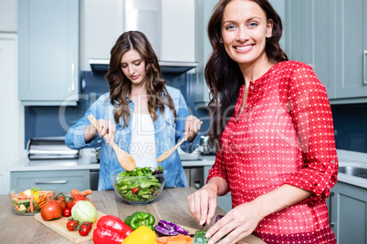 Happy female friends preparing vegetable salad