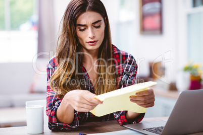 Tensed young woman looking at document