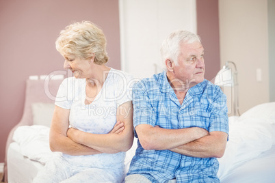 Serious senior couple sitting on bed at home