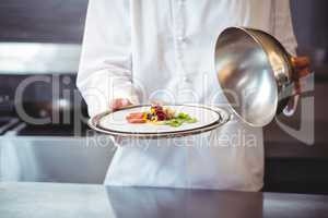 Chef raising a bell of a dish