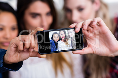 Female friends taking selfie with mobile phone at home