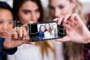 Female friends taking selfie with mobile phone at home