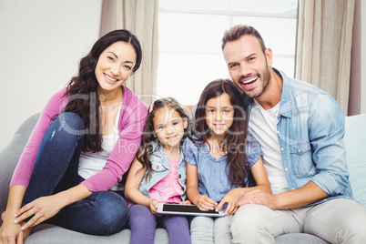 Family with tablet computer sitting on sofa