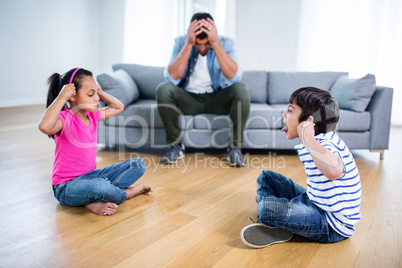 Annoyed father sitting on sofa while kids fighting