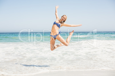 Carefree woman in bikini jumping on the beach