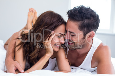 Smiling couple hugging while lying on b