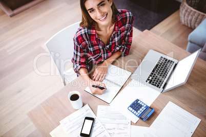 High angle portrait of smiling woman writing in notepad
