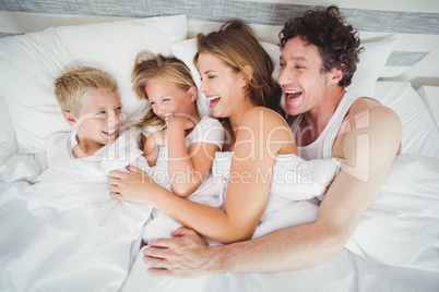 High angle view of smiling family enjoying on bed