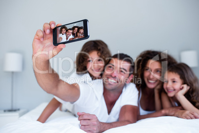 Happy family taking a selfie on bed