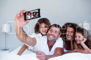 Happy family taking a selfie on bed