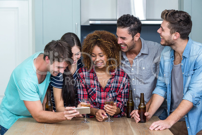 Multi-ethnic friends looking in mobile phone at home