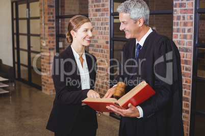 Male lawyer discussing over book with female colleague