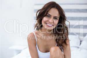 Beautiful young woman sitting on bed at home