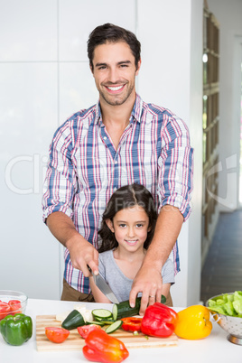 Portrait of happy father cutting vegetables with daughter