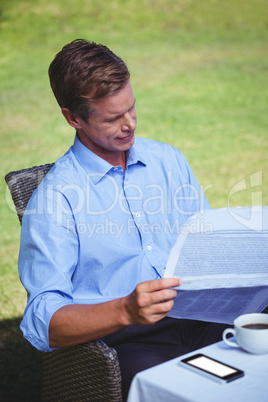 Handsome businessman having coffee and reading the news