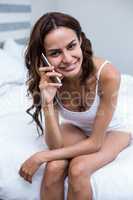 Beautiful woman talking on mobile phone on bed