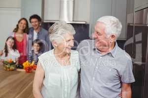 Happy grandparents with family in kitchen