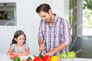 Father cutting vegetables with daughter