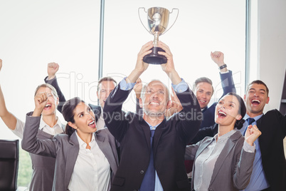 Winning business team with an executive holding trophy