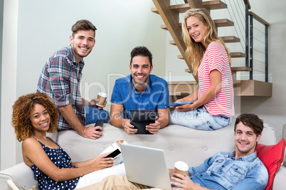 Happy young friends using modern technologies on sofa