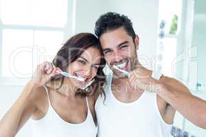 Happy couple brushing teeth in bathroom