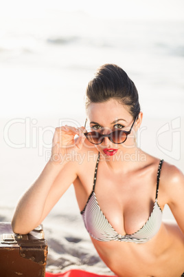 Glamorous woman in bikini looking over sunglasses