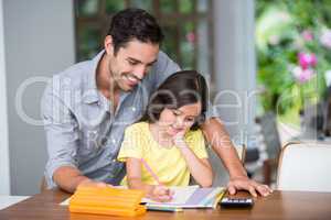 Smiling father assisting daughter with homework