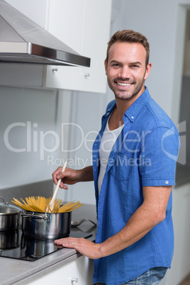Young man cooking spaghetti