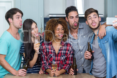 Friends making faces while taking selfie in kitchen