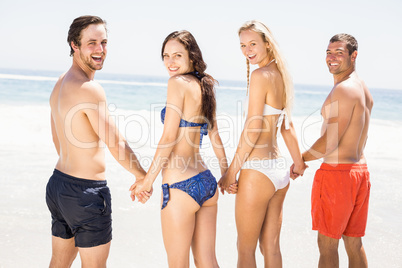 Happy friends holding hands together on the beach