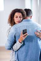Woman checking her mobile phone while embracing a man
