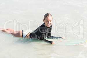 Happy woman lying on surfboard