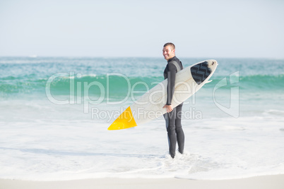 Surfer standing on the beach with a surfboard