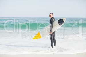 Surfer standing on the beach with a surfboard