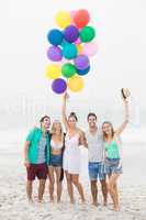 Group of friends standing on the beach with balloons