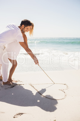 Couple drawing heart on sand