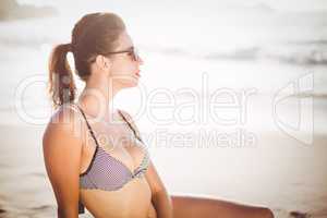 Glamorous woman in bikini sitting on the beach