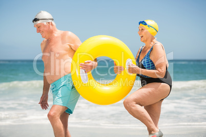 Senior couple with swimming ring at the beach