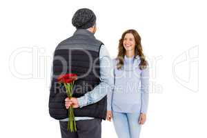 Man hiding a rose behind his back from his woman