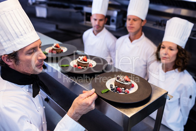 Head chef inspecting dessert plates on at order station