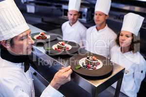 Head chef inspecting dessert plates on at order station