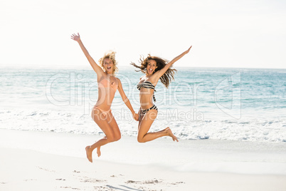 Beautiful excited friends jumping on the beach