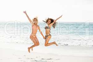Beautiful excited friends jumping on the beach