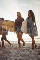 Beautiful friends walking with surfboards