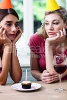 Sad friends sitting at table during birthday party