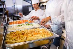 Chefs standing at serving trays of pasta