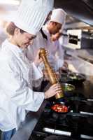 Chef sprinkling pepper on tomatos