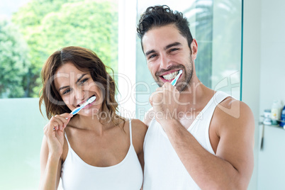 Happy young couple brushing teeth