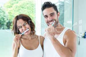 Happy young couple brushing teeth