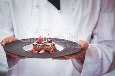 Chef holding a plate with a dessert